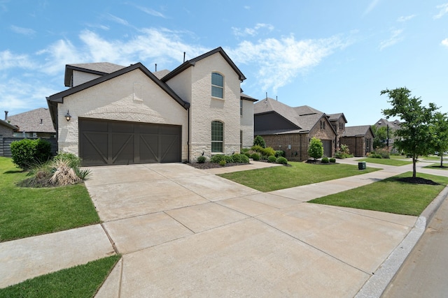 7020 Cross Point Ln, Little Elm, TX 76227 - french country inspired facade with a front yard, an attached garage, concrete driveway, and brick siding