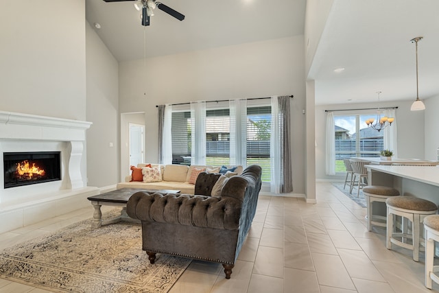 7020 Cross Point Ln, Little Elm, TX 76227 - living area featuring high vaulted ceiling, a ceiling fan, a chandelier, a warm lit fireplace, and baseboards