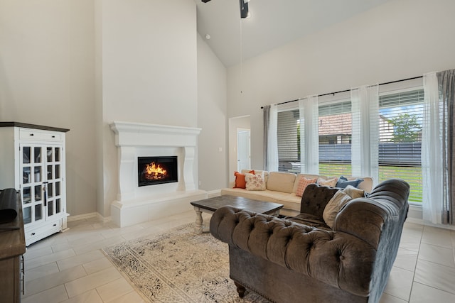 7020 Cross Point Ln, Little Elm, TX 76227 - living area featuring high vaulted ceiling, a ceiling fan, a lit fireplace, tile patterned floors, and baseboards