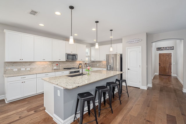 1205 Glacier Ct, Celina, TX 75009 - kitchen featuring stainless steel appliances, a sink, wood finished floors, decorative backsplash, and a center island with sink