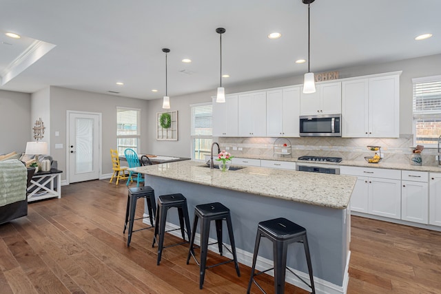 1205 Glacier Ct, Celina, TX 75009 - kitchen with a sink, stainless steel microwave, tasteful backsplash, a breakfast bar, and black gas stovetop