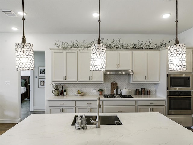 2624 Bellevue, The Colony, TX 75056 - kitchen featuring stainless steel oven, built in microwave, under cabinet range hood, gas stovetop, and tasteful backsplash