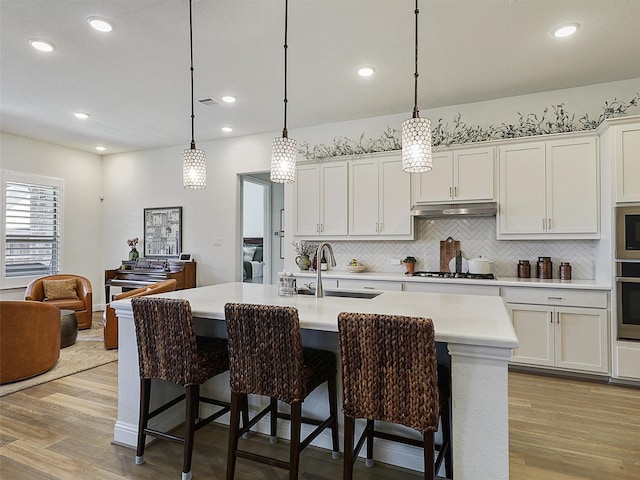2624 Bellevue, The Colony, TX 75056 - kitchen featuring a sink, backsplash, light wood-style flooring, light countertops, and stainless steel oven