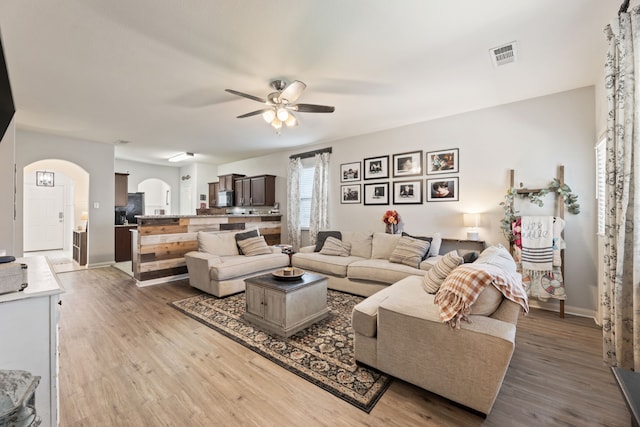 1615 White Mountain Way, Princeton, TX 75407 - living room with arched walkways, ceiling fan, wood finished floors, and baseboards