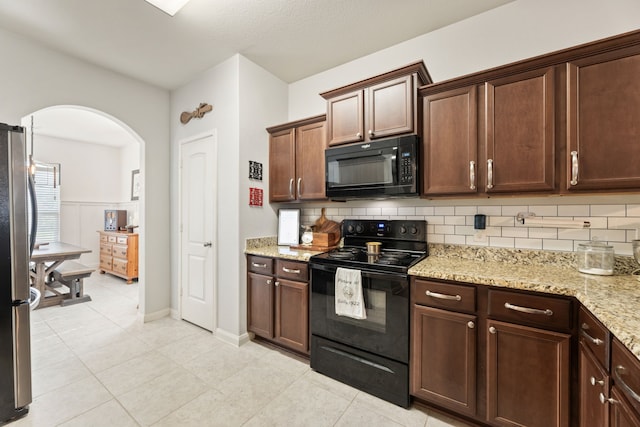 1615 White Mountain Way, Princeton, TX 75407 - kitchen with black appliances, arched walkways, tasteful backsplash, light stone counters, and light tile patterned flooring