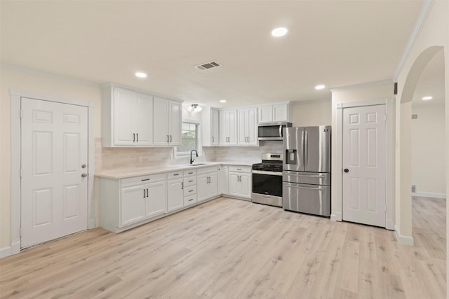 2810 Altman Dr, Irving, TX 75062 - kitchen with stainless steel appliances, crown molding, white cabinets, decorative backsplash, and light countertops