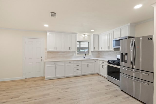 2810 Altman Dr, Irving, TX 75062 - kitchen featuring appliances with stainless steel finishes, a sink, white cabinets, tasteful backsplash, and recessed lighting
