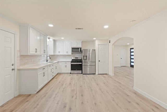 2810 Altman Dr, Irving, TX 75062 - kitchen with appliances with stainless steel finishes, arched walkways, a sink, ornamental molding, and tasteful backsplash