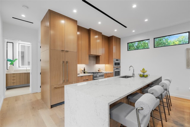 5029 Pershing St, Dallas, TX 75206 - kitchen with a sink, stainless steel appliances, modern cabinets, a kitchen breakfast bar, and light wood-style floors