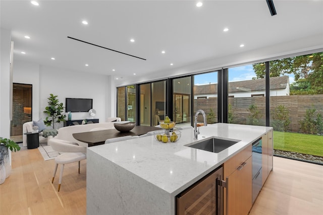 5029 Pershing St, Dallas, TX 75206 - kitchen with a sink, wine cooler, modern cabinets, light wood-type flooring, and a center island with sink