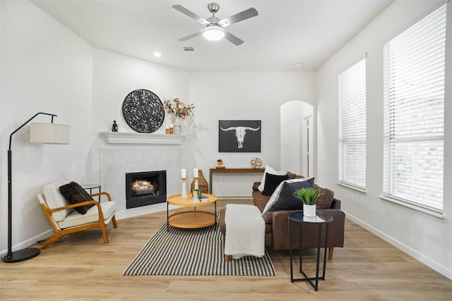 211 Windsong Way, Allen, TX 75002 - living room with arched walkways, a tile fireplace, wood finished floors, ceiling fan, and baseboards