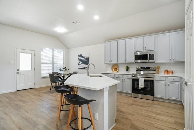 211 Windsong Way, Allen, TX 75002 - kitchen featuring stainless steel appliances, a sink, vaulted ceiling, decorative backsplash, and a breakfast bar area