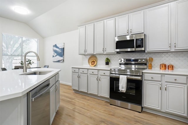 211 Windsong Way, Allen, TX 75002 - kitchen featuring appliances with stainless steel finishes, a sink, vaulted ceiling, decorative backsplash, and light countertops