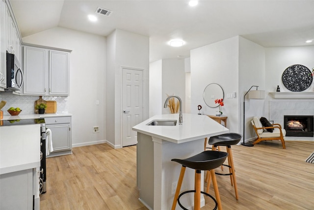 211 Windsong Way, Allen, TX 75002 - kitchen with stainless steel microwave, light wood finished floors, a sink, a kitchen breakfast bar, and baseboards
