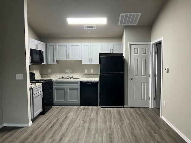 6108 Abrams Rd Unit 215, Dallas, TX 75231 - kitchen with black appliances, a sink, wood finished floors, light countertops, and baseboards
