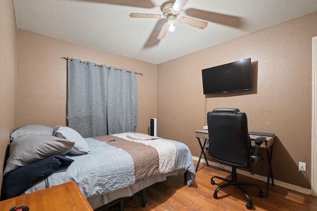 419 NW Murphy Rd, Burleson, TX 76028 - bedroom with wood finished floors, an office area, a ceiling fan, and a textured wall