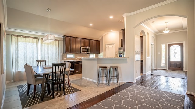 4100 Fanita Pl, Denton, TX 76210 - dining room featuring ornamental molding, arched walkways, hardwood / wood-style floors, baseboards, and lofted ceiling