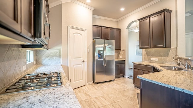 4100 Fanita Pl, Denton, TX 76210 - kitchen with stainless steel appliances, crown molding, a sink, arched walkways, and dark brown cabinets