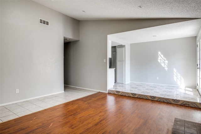 6646 E Lovers Ln Unit 602, Dallas, TX 75214 - spare room with wood finished floors, baseboards, vaulted ceiling, and a textured ceiling