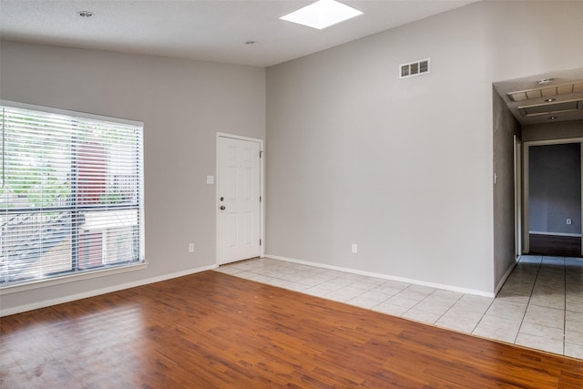6646 E Lovers Ln Unit 602, Dallas, TX 75214 - spare room featuring a skylight, light wood-type flooring, and baseboards