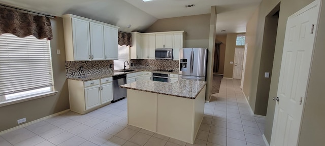 301 Crepe Myrtle Dr, Euless, TX 76039 - kitchen featuring appliances with stainless steel finishes, plenty of natural light, backsplash, lofted ceiling, and white cabinetry