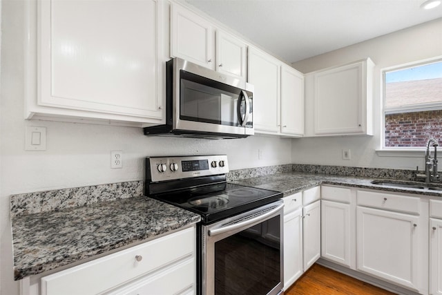 8109 Dripping Springs Dr, Fort Worth, TX 76134 - kitchen with appliances with stainless steel finishes, a sink, white cabinetry, and dark stone counters
