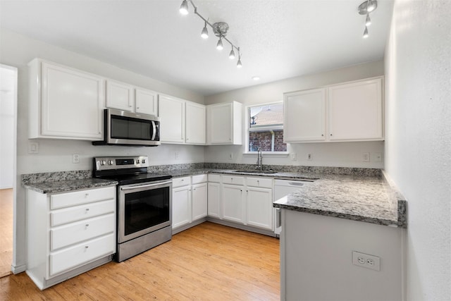 8109 Dripping Springs Dr, Fort Worth, TX 76134 - kitchen with appliances with stainless steel finishes, a sink, rail lighting, and white cabinetry