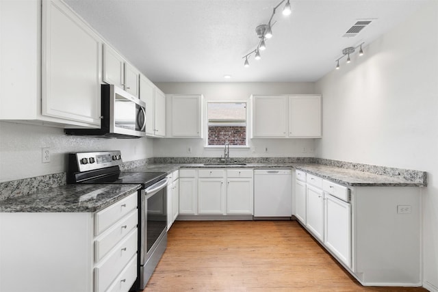 8109 Dripping Springs Dr, Fort Worth, TX 76134 - kitchen featuring stainless steel appliances, a sink, white cabinets, dark stone countertops, and light wood finished floors