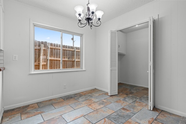 108 Mockingbird Ln, Hillsboro, TX 76645 - unfurnished dining area featuring crown molding, a chandelier, a textured ceiling, stone tile floors, and baseboards