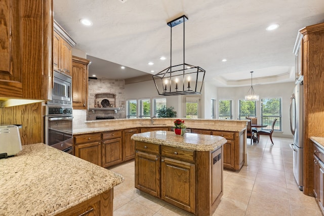 499 Savannah Hill Ln, Rockwall, TX 75032 - kitchen featuring appliances with stainless steel finishes, brown cabinetry, a center island, plenty of natural light, and recessed lighting
