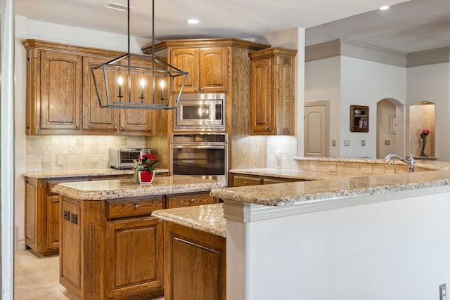 499 Savannah Hill Ln, Rockwall, TX 75032 - kitchen with appliances with stainless steel finishes, light stone countertops, brown cabinets, a center island, and tasteful backsplash