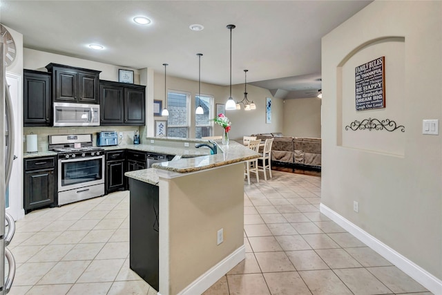 6158 Stillhouse Ln, Fort Worth, TX 76179 - kitchen with stainless steel appliances, a peninsula, light tile patterned floors, dark cabinets, and open floor plan
