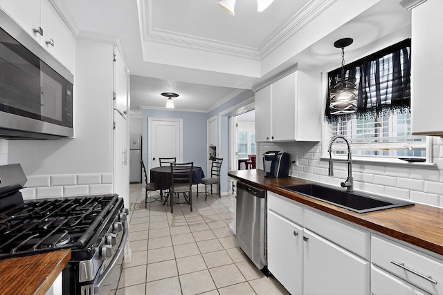 2913 Harlan Dr, Mesquite, TX 75150 - kitchen with wood counters, stainless steel appliances, a sink, light tile patterned floors, and tasteful backsplash
