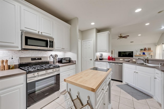 1301 Shell Beach Dr, Little Elm, TX 75068 - kitchen with appliances with stainless steel finishes, a sink, a ceiling fan, white cabinets, and tasteful backsplash