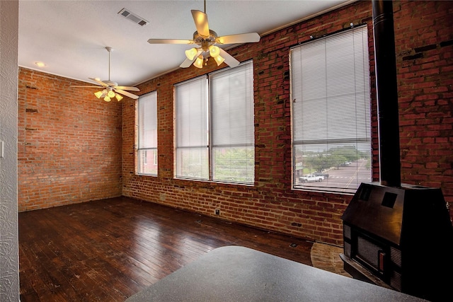1213 Washington St Unit B, Commerce, TX 75428 - unfurnished dining area with a wood stove, hardwood / wood-style floors, brick wall, and ceiling fan
