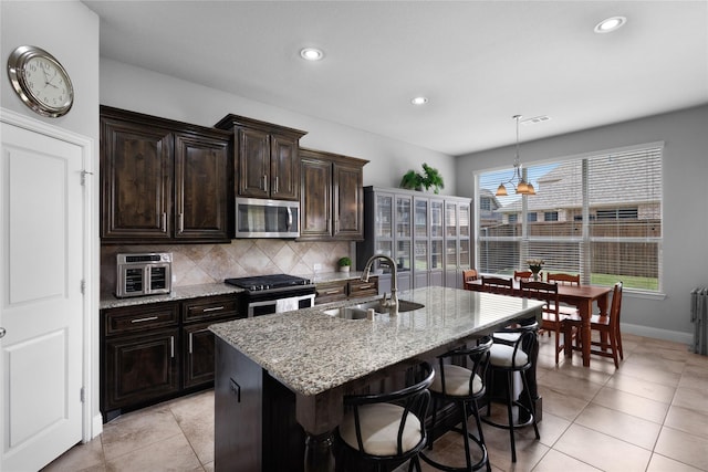 1211 Great Meadows Dr, Wylie, TX 75098 - kitchen with stainless steel appliances, a sink, a center island with sink, tasteful backsplash, and light stone counters