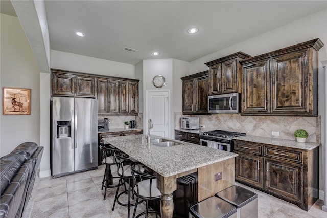1211 Great Meadows Dr, Wylie, TX 75098 - kitchen featuring appliances with stainless steel finishes, a sink, light stone counters, a kitchen breakfast bar, and decorative backsplash