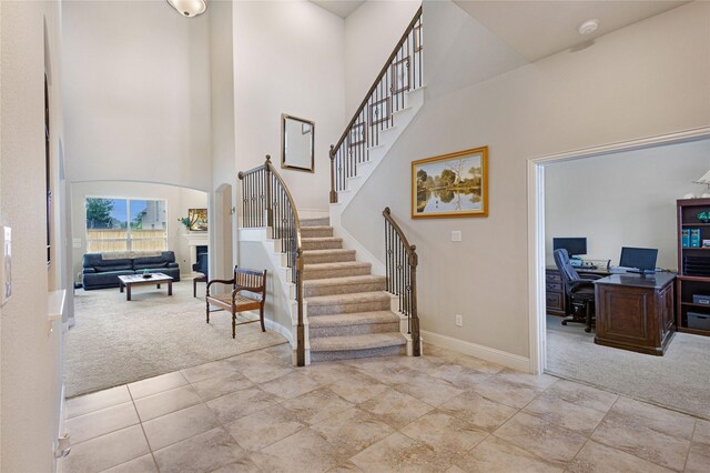 1211 Great Meadows Dr, Wylie, TX 75098 - entryway featuring light carpet, a towering ceiling, baseboards, stairway, and a glass covered fireplace