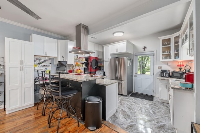 2832 Forest Ave, Fort Worth, TX 76112 - kitchen featuring freestanding refrigerator, island range hood, white cabinetry, a center island, and light stone countertops