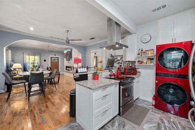 2832 Forest Ave, Fort Worth, TX 76112 - kitchen with stainless steel electric range oven, stacked washer and clothes dryer, a ceiling fan, wall chimney range hood, and open floor plan