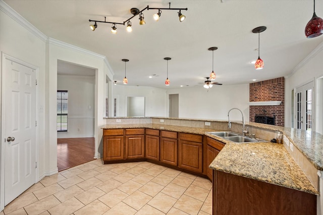 104 Spring Creek Dr, Waxahachie, TX 75165 - kitchen featuring a sink, a brick fireplace, crown molding, a ceiling fan, and brown cabinets