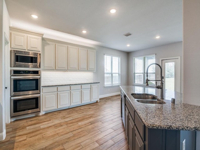 1517 Port Millstone Trl, Wylie, TX 75098 - kitchen with a sink, stainless steel appliances, light wood-style flooring, light stone countertops, and baseboards