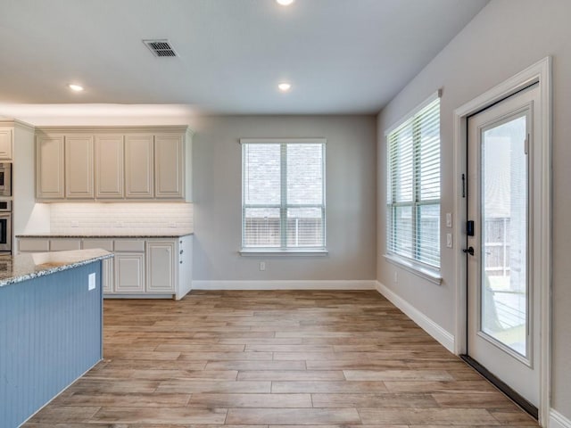1517 Port Millstone Trl, Wylie, TX 75098 - kitchen featuring light stone counters, stainless steel oven, light wood finished floors, decorative backsplash, and recessed lighting