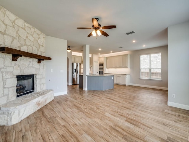 1517 Port Millstone Trl, Wylie, TX 75098 - unfurnished living room featuring ceiling fan, baseboards, a fireplace, light wood-style flooring, and a sink