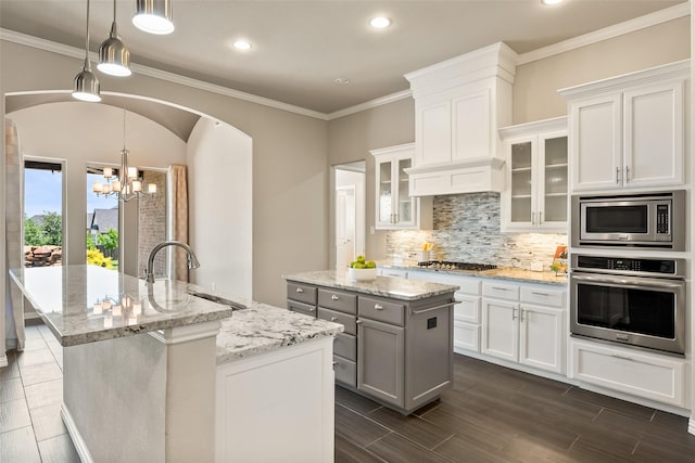 704 Prairie Timber Rd, Burleson, TX 76028 - kitchen featuring appliances with stainless steel finishes, a kitchen island with sink, a sink, arched walkways, and backsplash