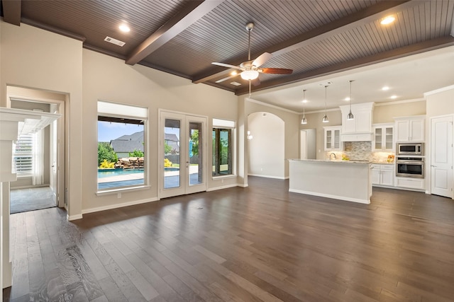 704 Prairie Timber Rd, Burleson, TX 76028 - unfurnished living room featuring beamed ceiling, arched walkways, dark wood finished floors, baseboards, and ceiling fan