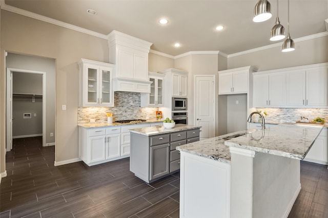 704 Prairie Timber Rd, Burleson, TX 76028 - kitchen with an island with sink, stainless steel appliances, tasteful backsplash, white cabinetry, and crown molding