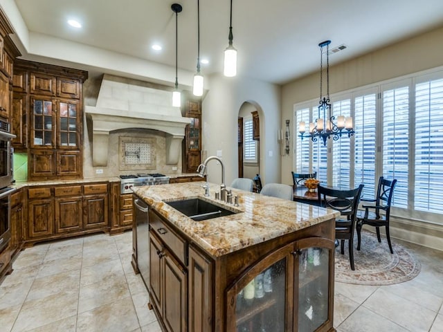 656 Clearwater Dr, Irving, TX 75039 - kitchen featuring a sink, arched walkways, appliances with stainless steel finishes, an island with sink, and glass insert cabinets