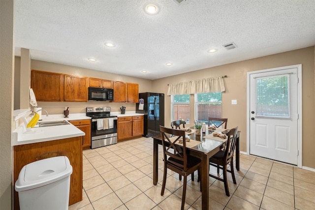2104 Blanco Ln, Justin, TX 76247 - kitchen featuring black appliances, a sink, brown cabinetry, light tile patterned floors, and light countertops