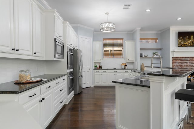 5617 Lindsey Dr, Plano, TX 75093 - kitchen featuring appliances with stainless steel finishes, dark countertops, white cabinets, a kitchen breakfast bar, and crown molding